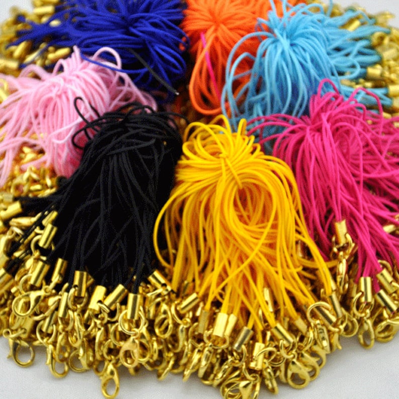 May include: A collection of colorful cords with gold lobster clasps. The cords are in various colors, including pink, blue, yellow, black, and red. The cords are made of a soft, flexible material and are perfect for making jewelry or crafts.