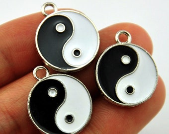 May include: Three silver charms with black and white enamel yin yang symbols. The charms have a loop at the top for attaching to a necklace or bracelet.