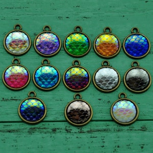 Puede incluir: Doce abalorios redondos iridiscentes de escamas de sirena con engastes de metal bronce antiguo. Los abalorios son de varios colores, incluyendo rosa, azul, verde, morado, naranja, plata y negro.