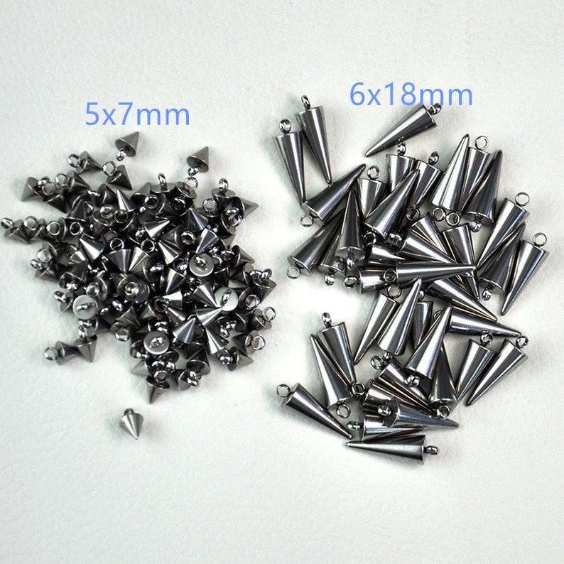 Puede incluir: Dos pilas de tachuelas piramidales de metal plateado con un bucle en la parte superior. La pila de la izquierda est&aacute; etiquetada como 5x7mm y la pila de la derecha est&aacute; etiquetada como 6x18mm.