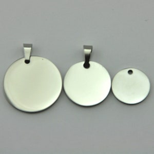 May include: Three silver metal round blank tags with a hole at the top. The tags are different sizes.