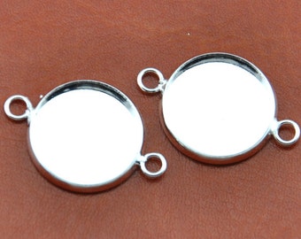 May include: Two silver-toned round pendant trays with a smooth, shiny finish. Each tray has two jump rings for attaching to a chain or cord.