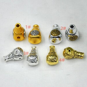 May include: A collection of decorative metal beads in various shapes and colors. The beads are gold and silver, with intricate designs. Some beads are bottle-shaped, while others are more rounded. The beads are numbered 1# through 4#.