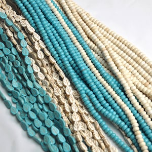 May include: A collection of turquoise and white beads, some with leaf designs, arranged in rows. The beads are strung on a cord and are ready to be used for jewelry making.