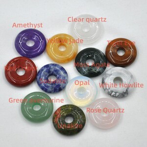 Pode incluir: Conjunto de 10 pingentes de pedras preciosas em forma de rosquinha em v&aacute;rias cores, incluindo ametista, quartzo transparente, jade amarelo, olho de tigre, &aacute;gata musgosa, opala, howlite branca, aventurina verde, unakita e quartzo rosa.