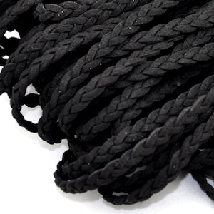 May include: Black braided cord made of suede leather. The cord is tightly woven and has a smooth, soft texture.