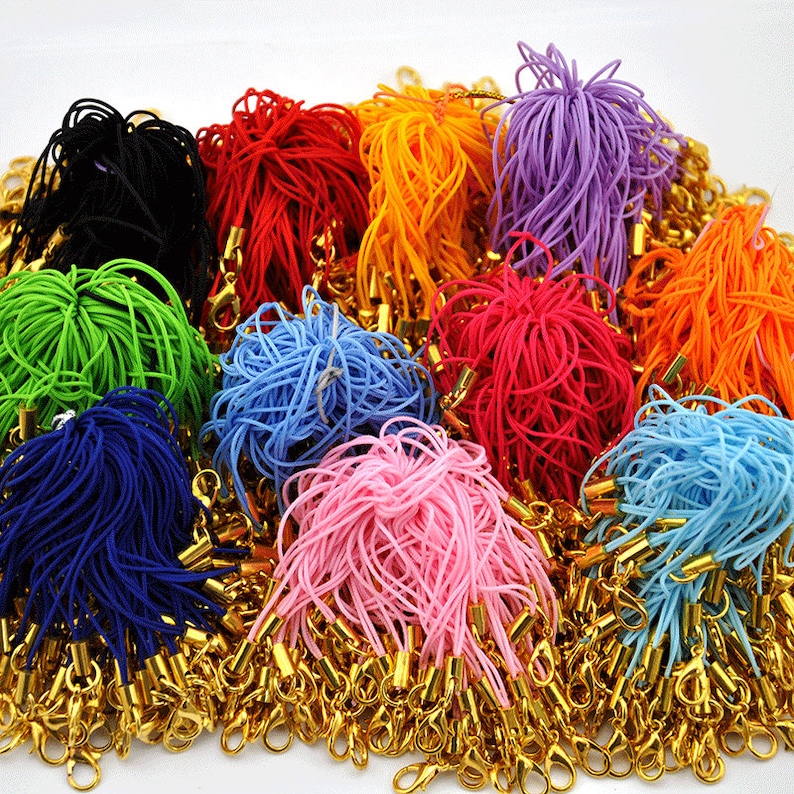 May include: A large assortment of colorful elastic cords with gold metal clasps. The cords are bundled together in a variety of colors, including black, red, orange, purple, green, blue, pink, and light blue.