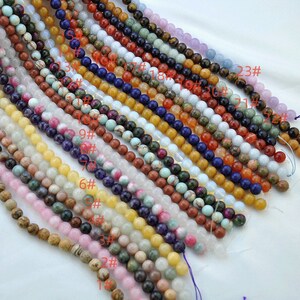 Puede incluir: Una colecci&oacute;n de 23 hileras de cuentas de piedras preciosas, cada hilera con un color y un patr&oacute;n diferentes. Las cuentas son redondas y lisas, y est&aacute;n dispuestas en una fila de arriba a abajo. Las cuentas son todas de aproximadamente el mismo tama&ntilde;o y est&aacute;n enhebradas en un hilo delgado. Las cuentas son de varios colores, incluyendo blanco, rosa, amarillo, verde, azul, marr&oacute;n y rojo.