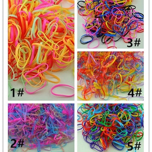 Pu&ograve; includere: Cinque pile di elastici colorati. Ogni pila &egrave; etichettata con un numero da 1 a 5. Gli elastici sono di vari colori, tra cui rosso, blu, verde, giallo e rosa.