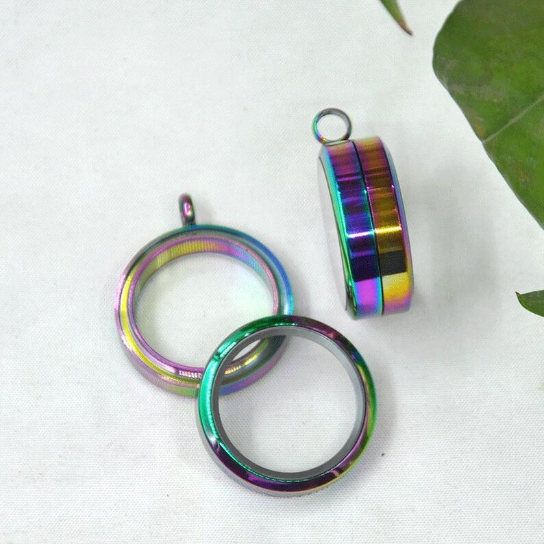 Puede incluir: Tres colgantes redondos de medall&oacute;n iridiscentes con un acabado plateado. Los medallones tienen un inserto de vidrio transparente y son perfectos para agregar un toque personal a las joyas.