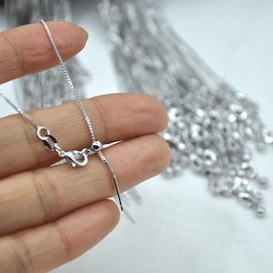 May include: A silver chain necklace with a silver clasp and a silver adjustable cord. The chain is made of small, round links.