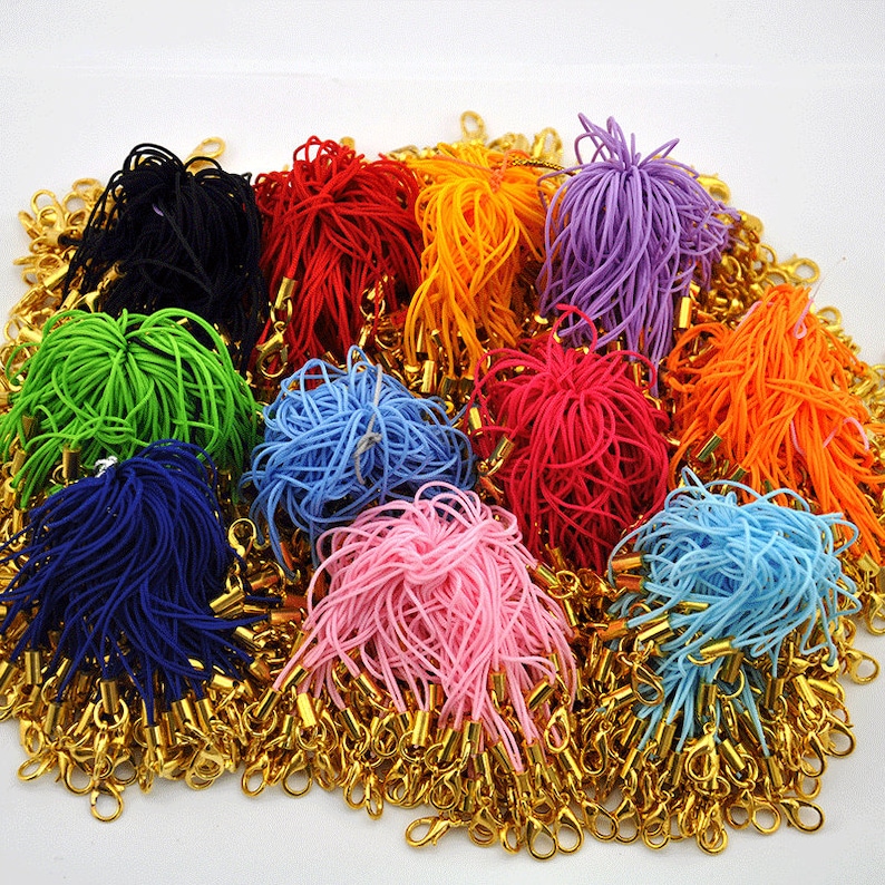 May include: A large assortment of colorful elastic cords with gold metal clasps. The cords are bundled together in various colors, including green, blue, pink, red, orange, purple, and black.