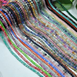 Puede incluir: Una colecci&oacute;n de cuentas de piedras preciosas en forma de coraz&oacute;n en varios colores, incluyendo rojo, verde, azul y morado. Las cuentas est&aacute;n ensartadas, creando hebras de componentes de joyer&iacute;a. La imagen muestra una variedad de texturas y tonos.