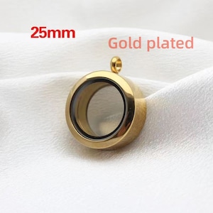 Puede incluir: Colgante de medall&oacute;n chapado en oro con un inserto de vidrio transparente. El medall&oacute;n tiene un di&aacute;metro de 25 mm.