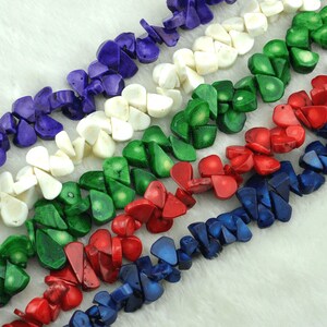 May include: Strands of colorful, irregular-shaped beads in shades of purple, white, green, red, and blue. The beads are arranged in diagonal rows, creating a textured and vibrant pattern. The beads appear to be made of a natural material, possibly stone or shell.