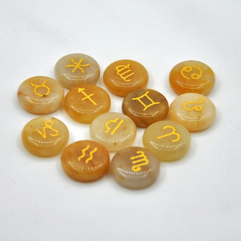 May include: Set of 12 yellow-toned gemstone coasters with gold zodiac symbols. Each coaster features a different zodiac sign.