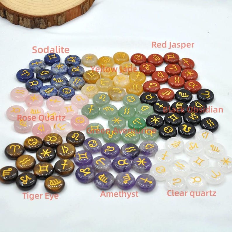 May include: A set of 12 zodiac signs, each carved from a different gemstone. The stones include sodalite, rose quartz, tiger eye, amethyst, clear quartz, red jasper, yellow jade, and green aventurine. Each stone is engraved with the corresponding zodiac symbol in gold.