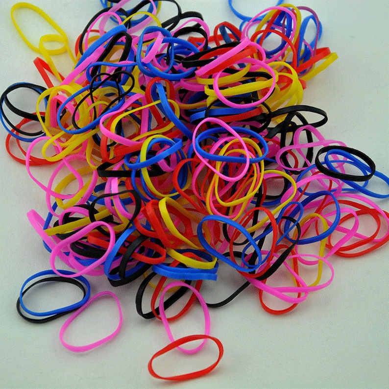 Pu&ograve; includere: Un grande mucchio di elastici colorati in rosa, rosso, giallo, blu e nero.