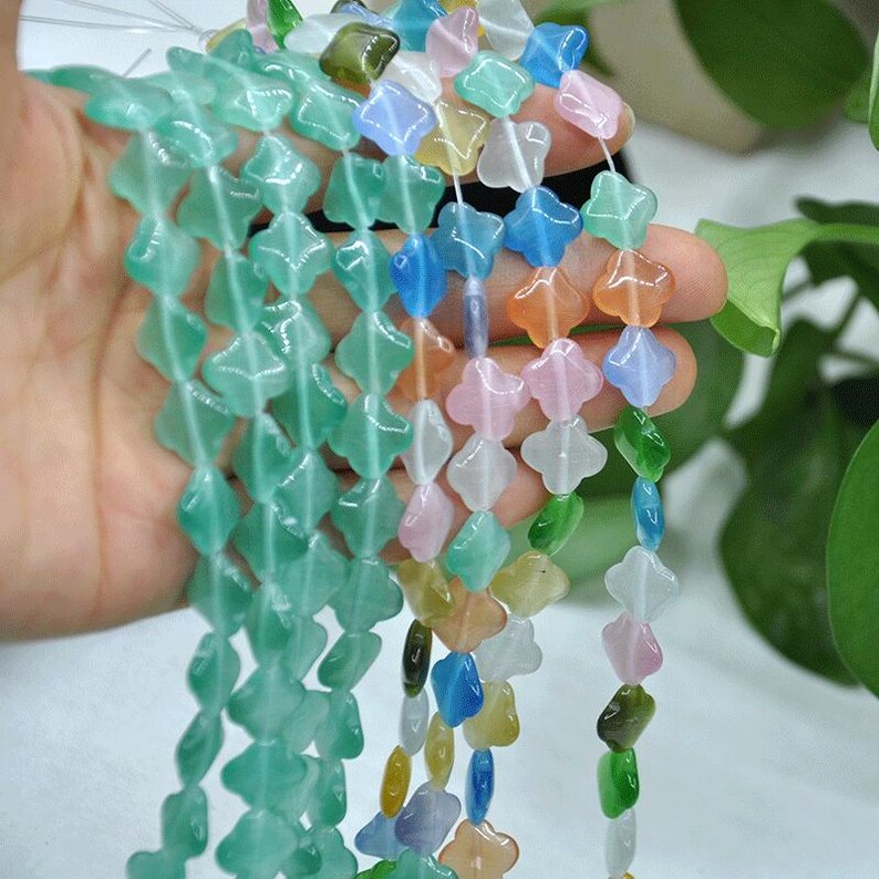 Puede incluir: Hebras de cuentas de piedras preciosas de colores en varias formas y colores, incluyendo verde, azul, rosa y naranja. Las cuentas se sostienen en una mano, mostrando sus vibrantes tonos y dise&ntilde;os &uacute;nicos. Ideal para la fabricaci&oacute;n de joyas.
