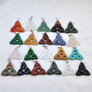 May include: Twenty-four pendants featuring a Celtic knot design carved from various gemstones, including green malachite, red jasper, blue lapis lazuli, and white quartz.