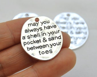 May include: Silver charm with the text "may you always have a shell in your pocket & sand between your toes".