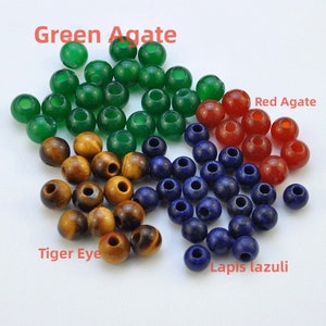 Könnte beinhalten: Sortiment an Edelsteinperlen, darunter grüner Achat, roter Achat, Tigerauge und Lapislazuli. Die Perlen sind rund und haben ein Loch in der Mitte zum Auf fädeln.