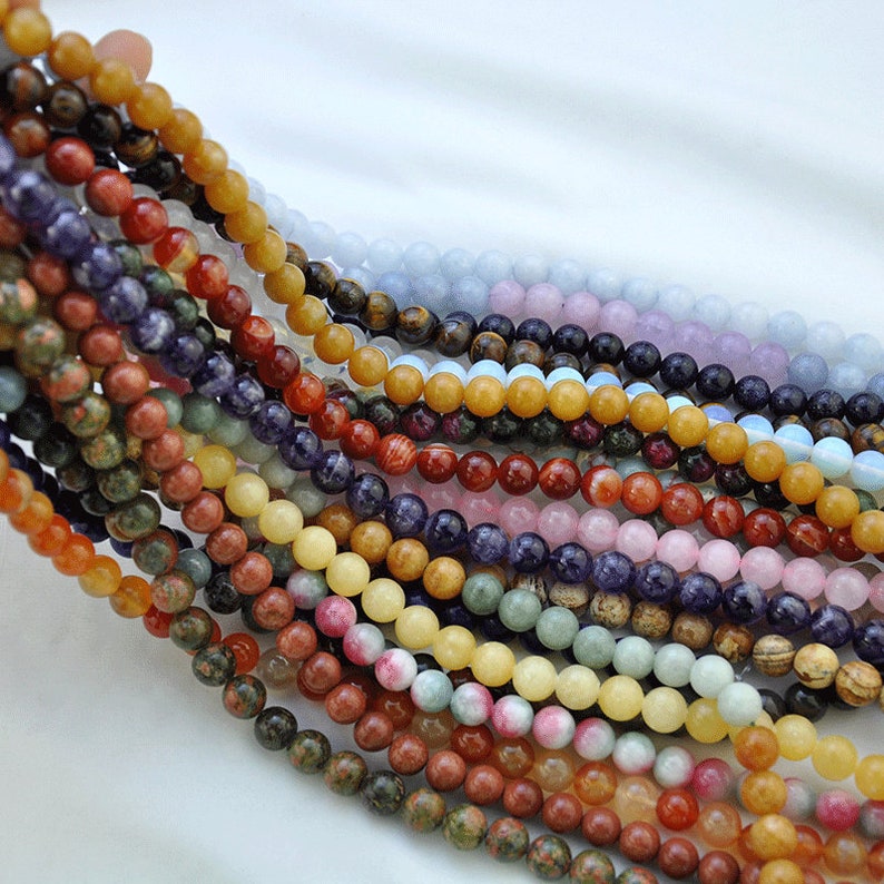 Puede incluir: Una variedad de cuentas de piedras preciosas en diferentes colores y texturas, incluyendo amarillo, rojo, verde, azul y morado. Las cuentas est&aacute;n dispuestas en filas, creando una exhibici&oacute;n colorida y visualmente atractiva.