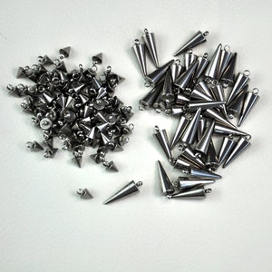 Puede incluir: Dos pilas de tachuelas de metal plateado en forma de cono con un bucle en la parte superior. Las tachuelas est&aacute;n dispuestas en un patr&oacute;n aleatorio.