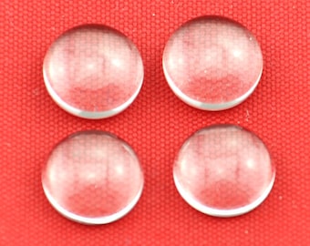 May include: Four clear glass cabochons, each with a slightly domed shape, are arranged in a square pattern on a red fabric background.