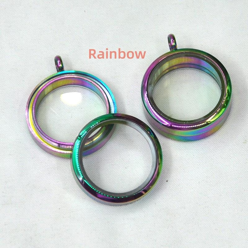 Puede incluir: Tres colgantes de medall&oacute;n de metal iridiscente arco&iacute;ris con inserciones de vidrio transparente. Los medallones tienen un bucle en la parte superior para sujetarlos a una cadena.