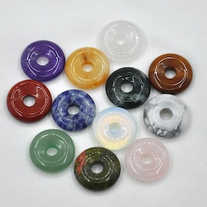 Pode incluir: Conjunto de 10 an&eacute;is de pedras preciosas em forma de rosquinha em v&aacute;rias cores, incluindo vermelho, verde, azul, roxo, branco, rosa, laranja e marrom.