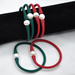 以下が含まれることがあります： 真珠のアクセントがついたシリコンブレスレットが4つ。緑のブレスレットが2つ、赤のブレスレットが2つです。