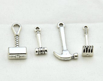 May include: Four silver-toned metal charms shaped like tools: a hammer, a mallet, a wrench, and a rake.