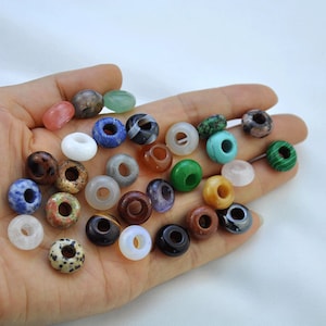 May include: Assortment of colorful donut-shaped gemstone beads. The beads are made of various natural stones, including agate, amethyst, carnelian, jasper, and turquoise.