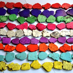 Puede incluir: Una hebra de cuentas de turquesa de colores, cada cuenta es una forma irregular única con un patrón moteado. Las cuentas están dispuestas en filas de diferentes colores, incluyendo rojo, morado, verde, rosa, blanco, naranja, turquesa y amarillo.