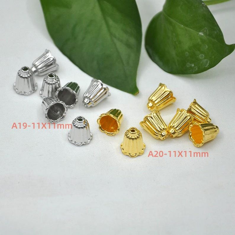 May include: Two sets of metal end caps for cords or jewelry. The first set is silver and the second set is gold. Each set has 6 end caps. The silver end caps are labeled A19-11X11mm and the gold end caps are labeled A20-11X11mm.