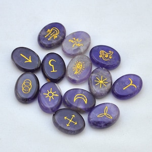 May include: Thirteen purple oval-shaped amethyst stones with gold symbols on each. The symbols include a crescent moon, a sun, a star, a cross, a circle with three dots, an arrow, a wave, a spiral, a crescent moon with a star, a crescent moon with a dot, a crescent moon with a line, and a crescent moon with a line and a dot.