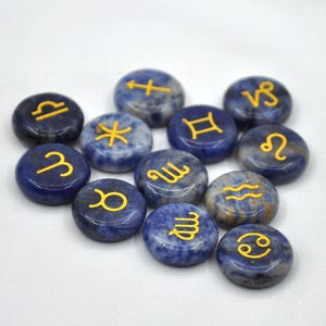 May include: Twelve blue and white gemstone zodiac signs with gold lettering. The signs are arranged in a circle on a white background.
