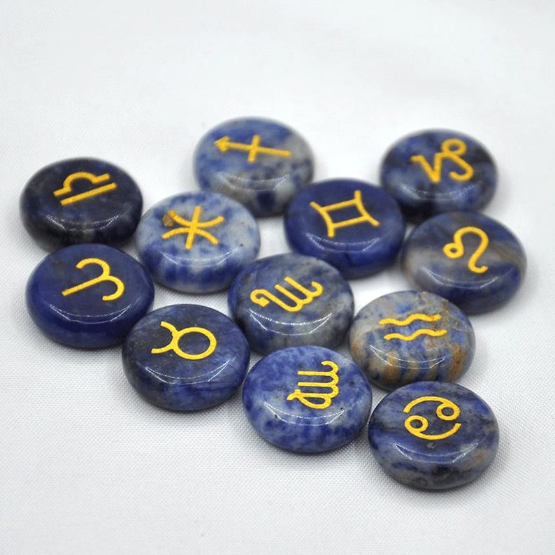 May include: Twelve blue and white gemstone zodiac signs with gold lettering. The signs are arranged in a circle on a white background.