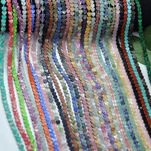 Puede incluir: Una colecci&oacute;n de cuentas en forma de coraz&oacute;n en varios colores, incluyendo rojo, verde, azul, morado y marr&oacute;n. Las cuentas est&aacute;n ensartadas, creando hebras de componentes de joyer&iacute;a coloridos. La imagen muestra una variedad de cuentas de piedras preciosas.