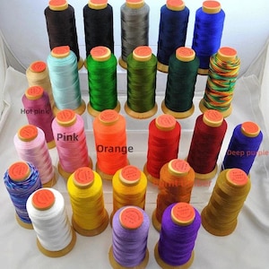 May include: A collection of colorful spools of thread in various shades, including brown, black, gray, blue, green, pink, orange, red, and yellow. Each spool has a wooden base and a yellow top. The image showcases a variety of sewing thread.