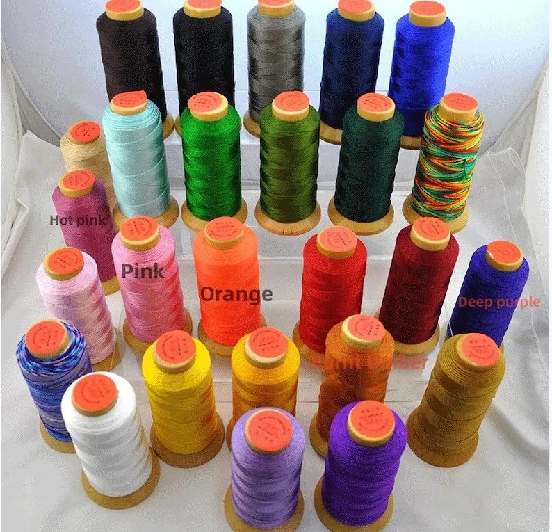 May include: A collection of colorful spools of thread in various shades, including brown, black, gray, blue, green, pink, orange, red, and yellow. Each spool has a wooden base and a yellow top. The image showcases a variety of sewing thread.