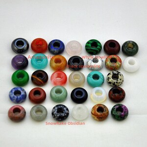 May include: Assortment of 25 gemstone donut beads in various colors, including green, red, blue, black, white, and brown. The beads have a hole in the center for stringing.