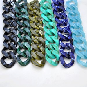 Puede incluir: Primer plano de seis cadenas de pl&aacute;stico de diferentes colores. Las cadenas est&aacute;n hechas de eslabones gruesos y robustos y son de color negro, verde, marr&oacute;n, turquesa, azul y azul claro.