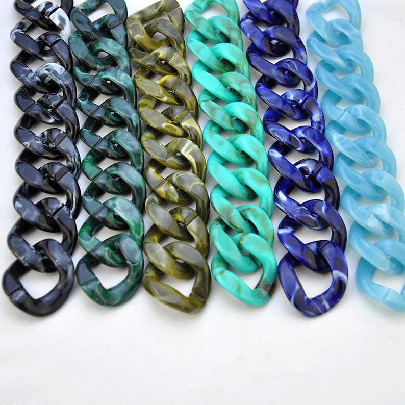 Puede incluir: Primer plano de seis cadenas de pl&aacute;stico de diferentes colores. Las cadenas est&aacute;n hechas de eslabones gruesos y robustos y son de color negro, verde, marr&oacute;n, turquesa, azul y azul claro.