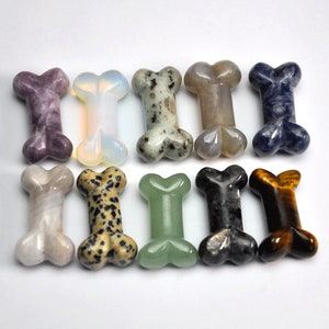 May include: Ten polished gemstone dog bone shaped charms in various colours and patterns, including purple, white, green, brown, black, and blue.