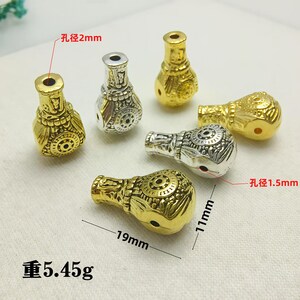 May include: An assortment of decorative beads in gold and silver tones. The beads are approximately 19mm long and 11mm wide, with a weight of 5.45 grams. The hole diameter is 2mm and 1.5mm. The beads have an ornate, textured design.