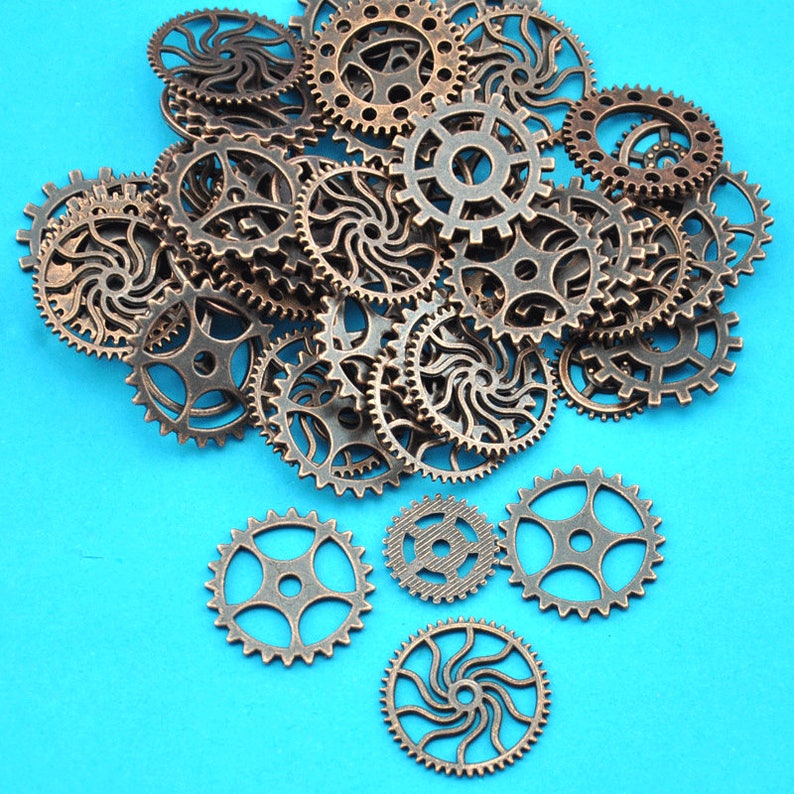 Puede incluir: Una colecci&oacute;n de engranajes de metal de color bronce antiguo de varios tama&ntilde;os y formas, esparcidos sobre un fondo azul brillante.