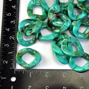 Puede incluir: Un mont&oacute;n de eslabones de cadena de pl&aacute;stico turquesa y marr&oacute;n. Los eslabones son de forma ovalada con un agujero cuadrado en el centro. Los eslabones tienen un di&aacute;metro de aproximadamente 2,5 cm.