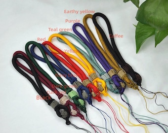 May include: A collection of colorful wrist straps in various shades, including red, yellow, and purple. Each strap features a woven design and a knotted end with a matching tassel. The image includes text labels indicating the color of each strap.
